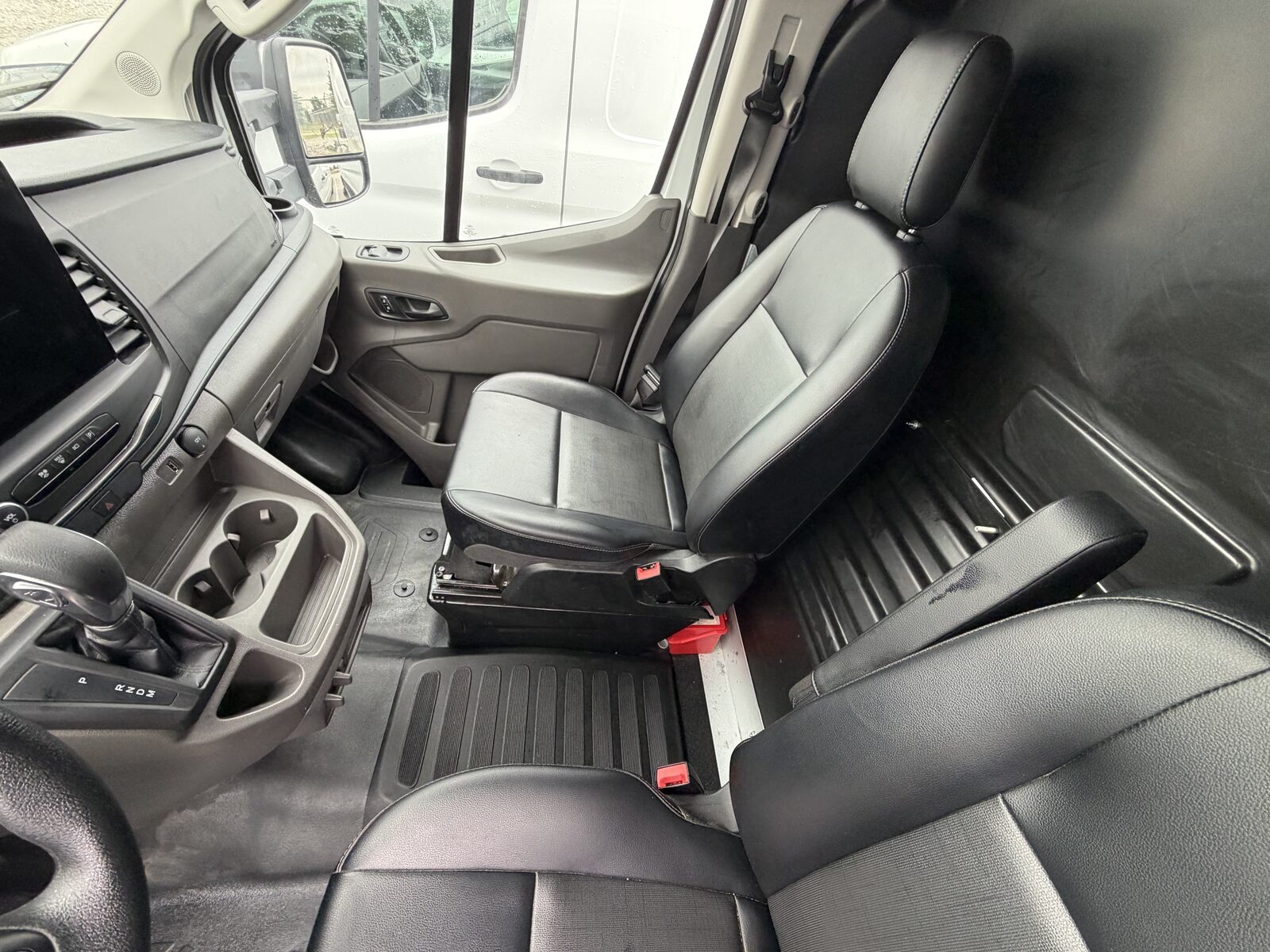 The same van interior after detailing: clean leather seats, polished floor, and tidy console.
